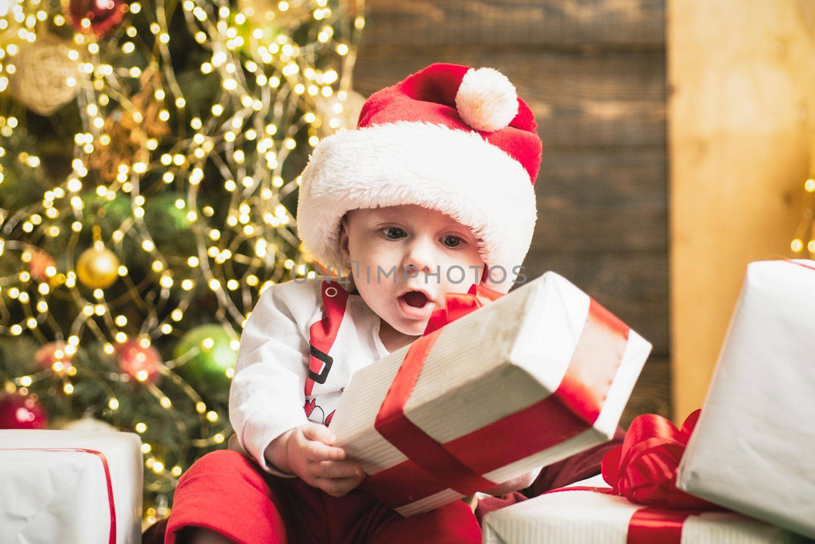 Surprised excited funny cute baby near the christmas tree. by Tverdokhlib