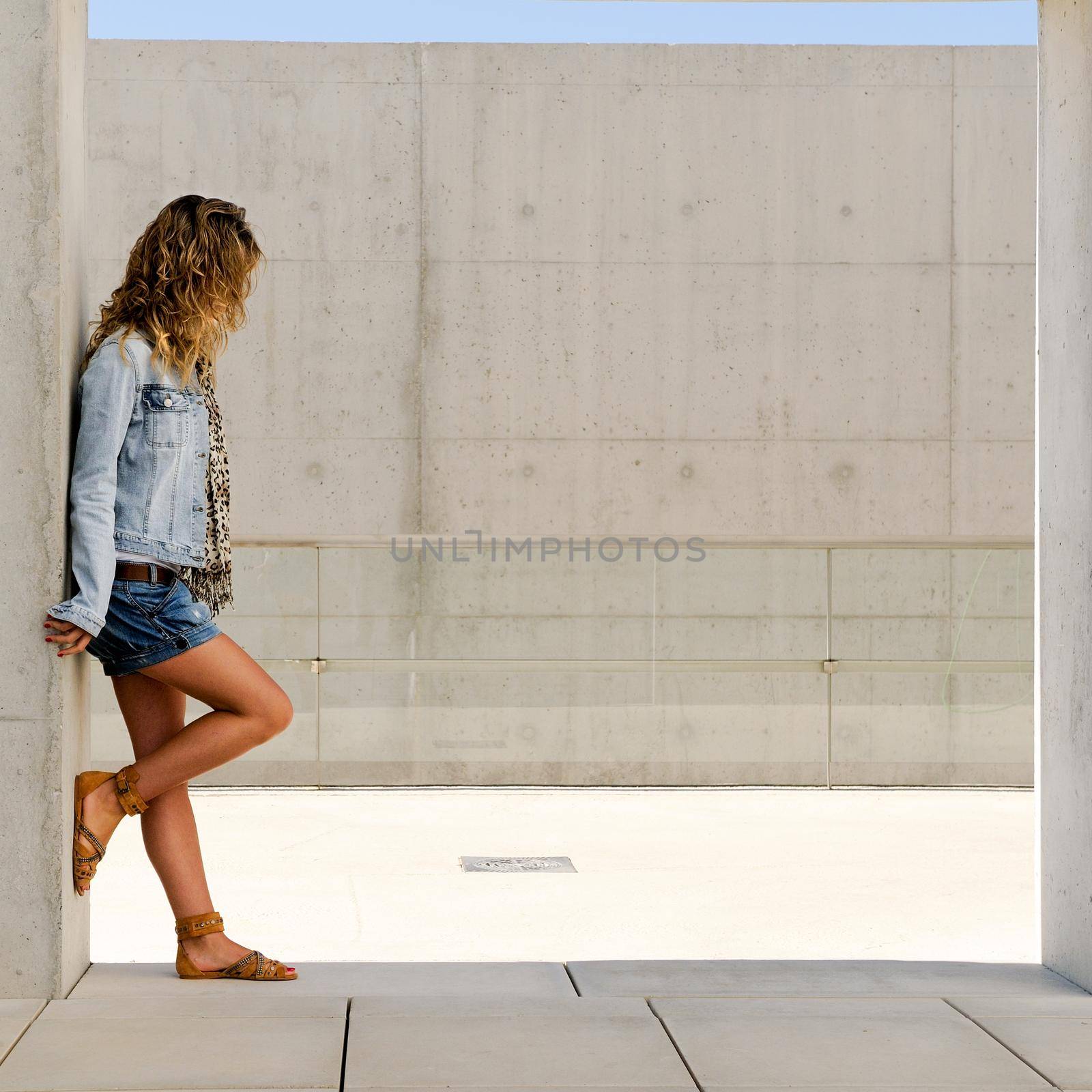 Portrait of a young blonde woman against urban wall