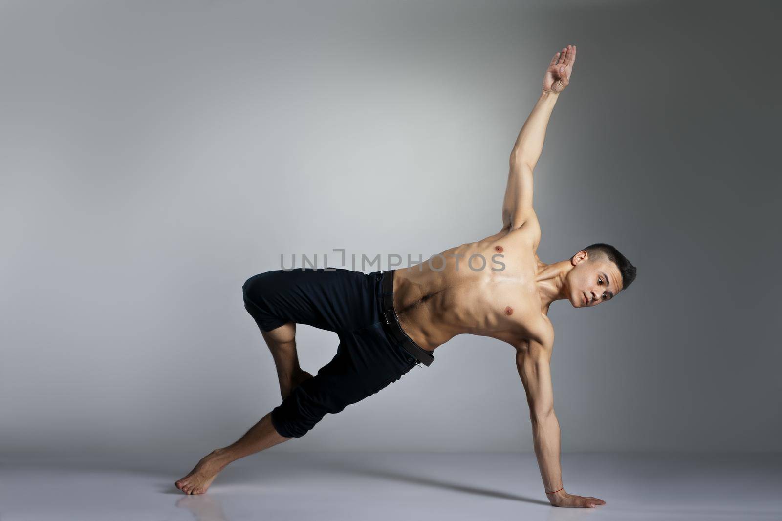 Young and stylish modern ballet dancer on grey background