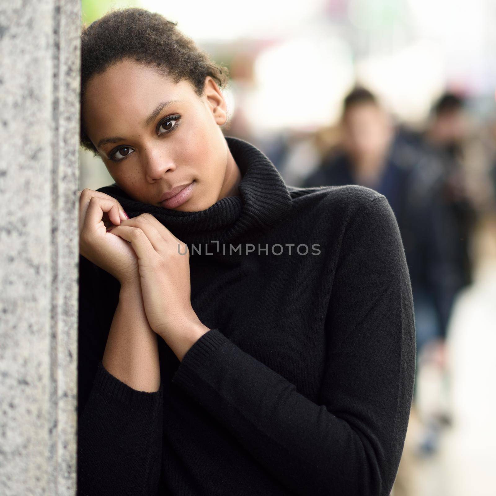 Young black female standing in an urban street. Mixed woman wearing poloneck sweater and skirt.