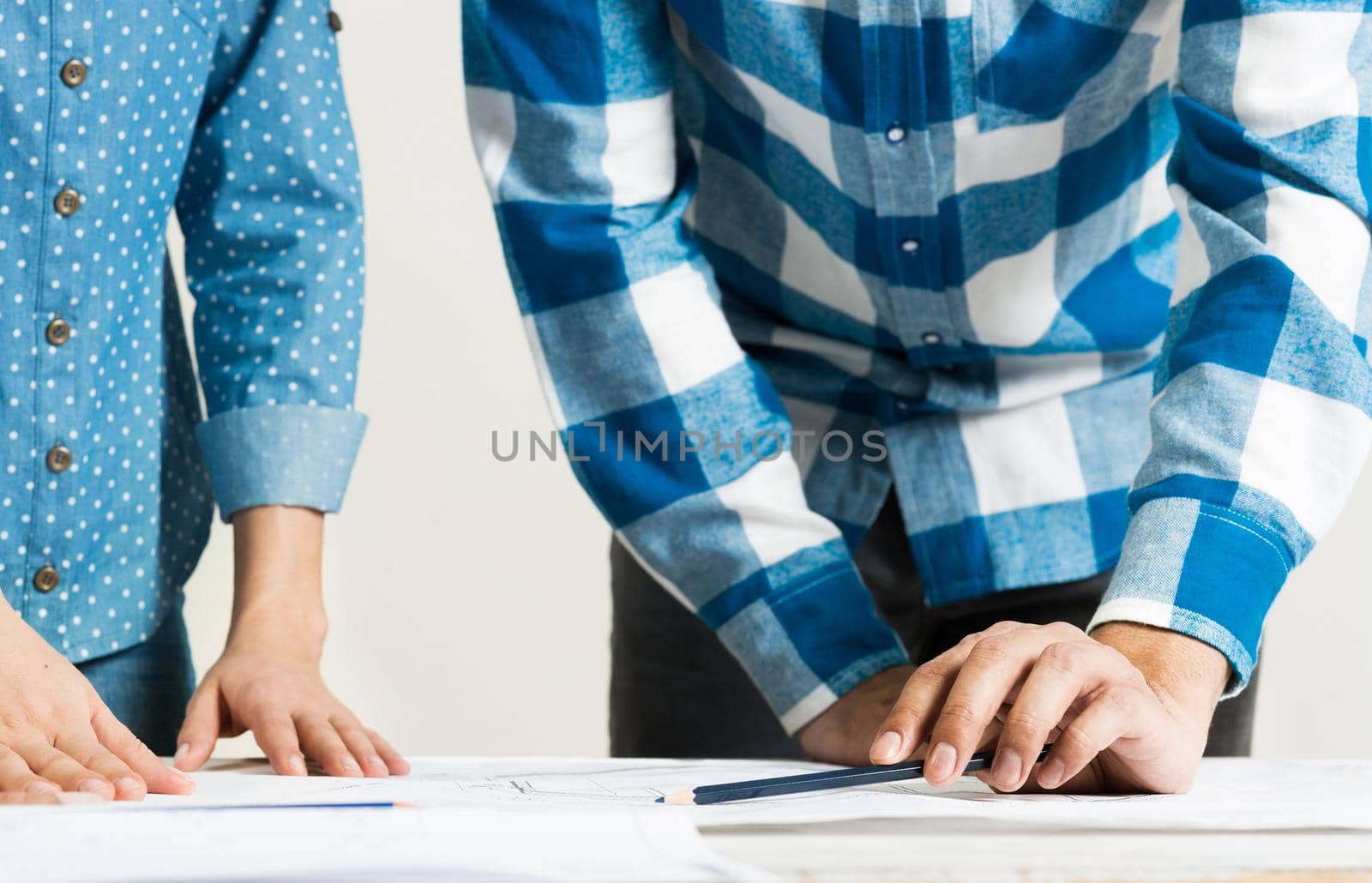 Design project discussing in architecture studio. Architect analyzing paper blueprint. Close up man hand pointing with pencil on construction drawing. Professional building, engineering and renovation