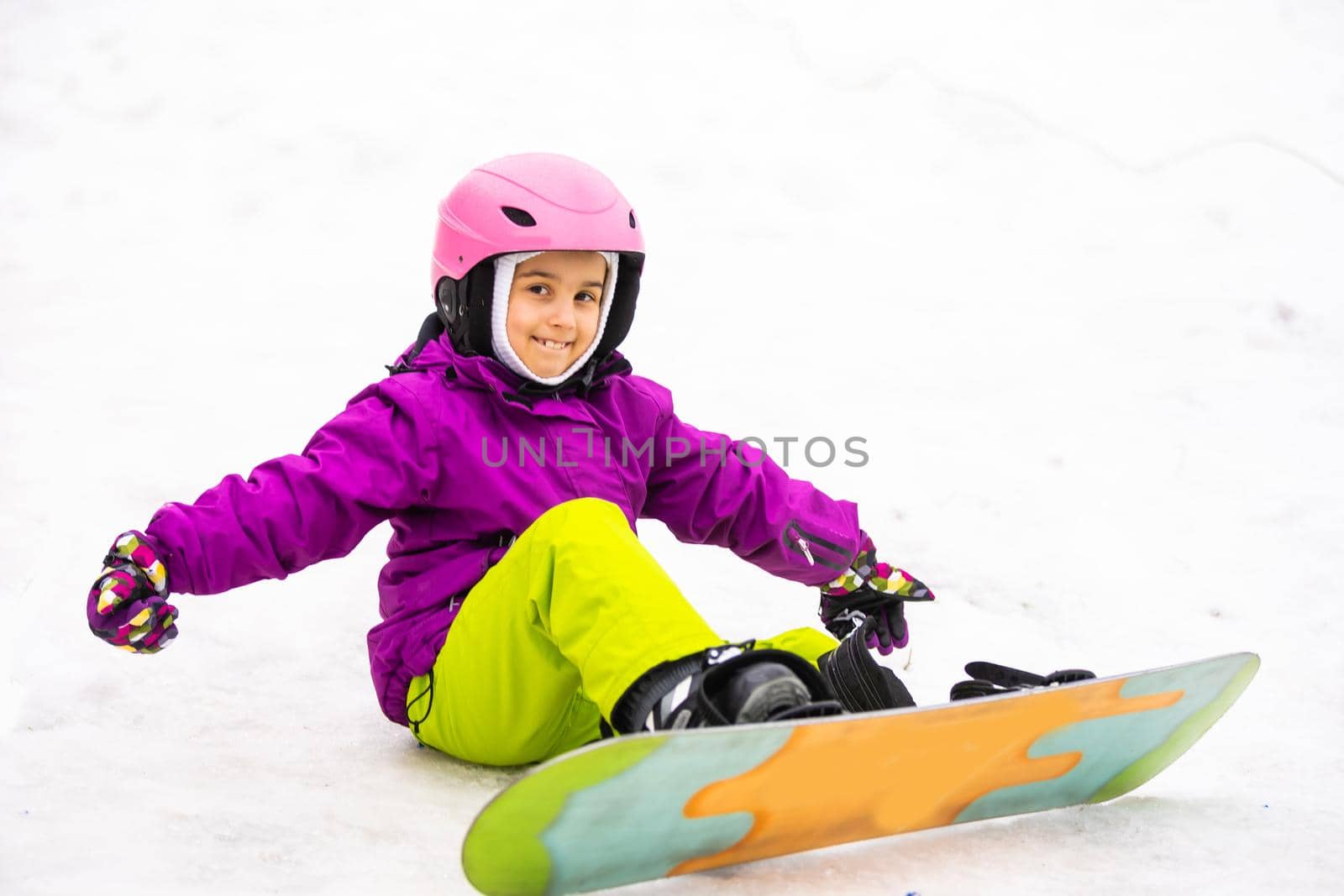 Little Cute Girl Snowboarding at ski resort in sunny winter day.