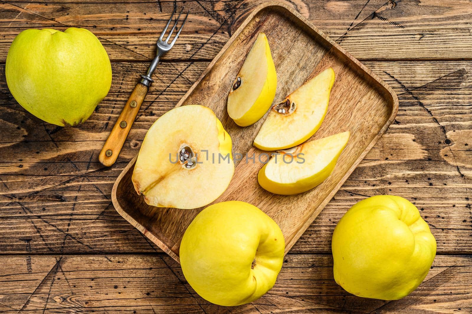 Cut yellow quince fruits in a wooden tray. wooden background. Top view by Composter