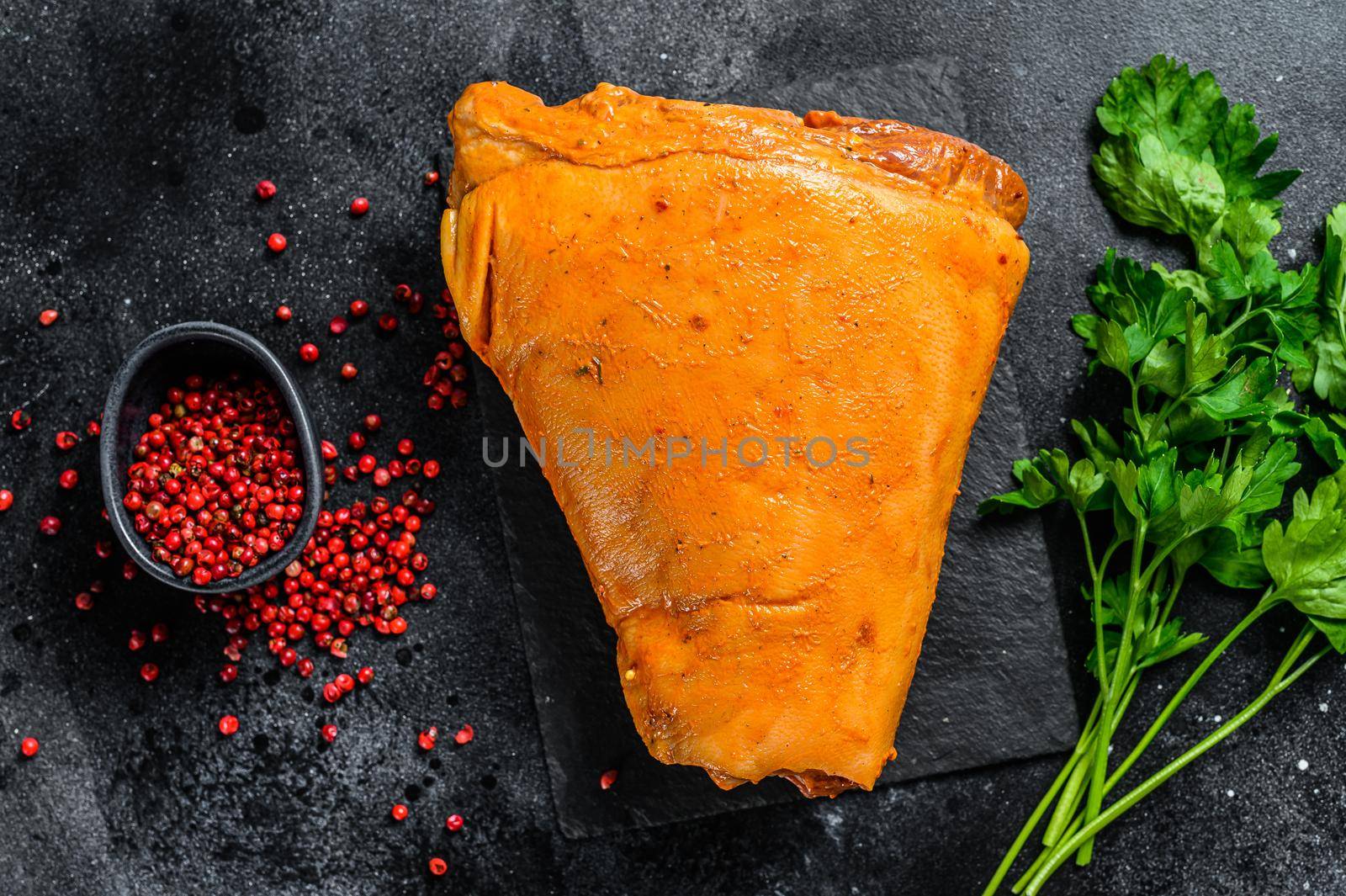 Raw pork leg with herbs and marinate on table. Black background. Top view.