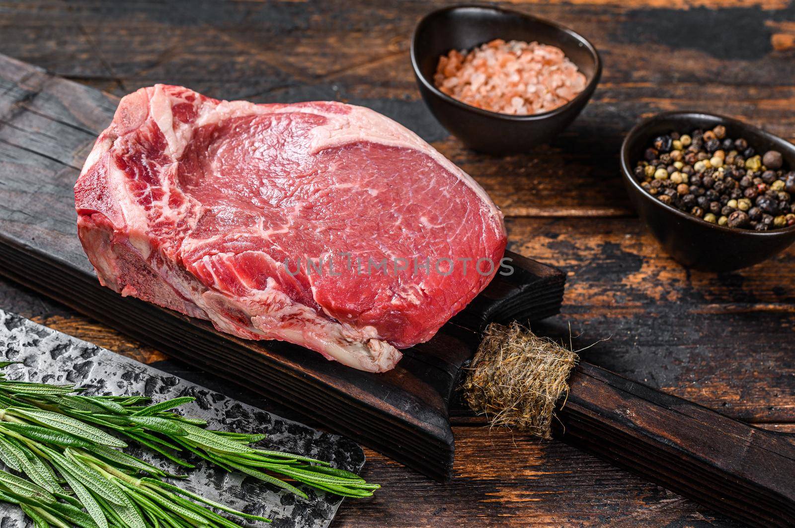 Raw beef meat Club or striploin on the bone steak. Dark wooden background. Top view.