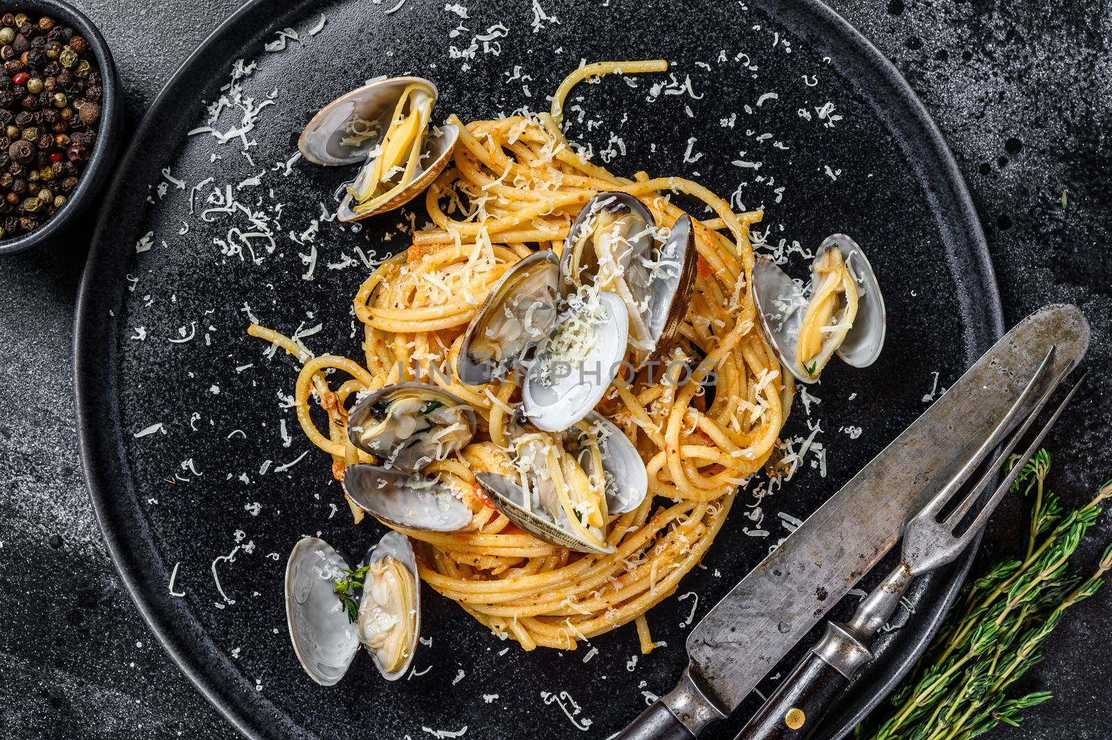 Seafood Spaghetti pasta with Clams vongole in a plate. Black background. Top view by Composter