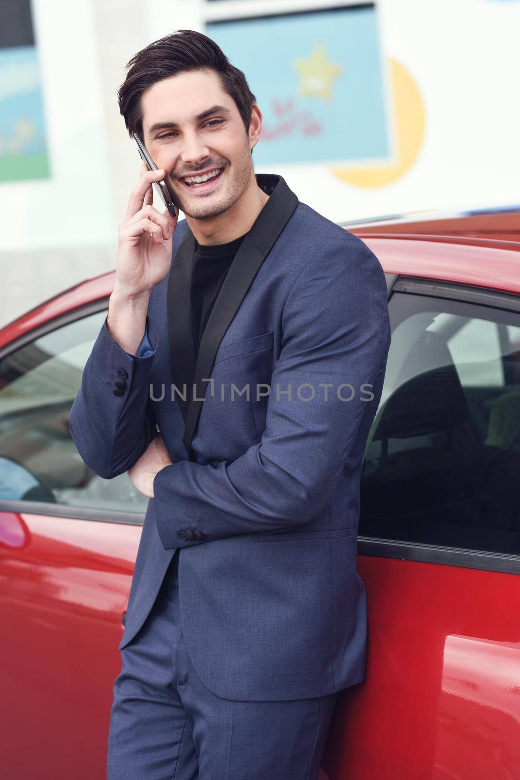 Young businessman talking with his mobile phone near a car by javiindy