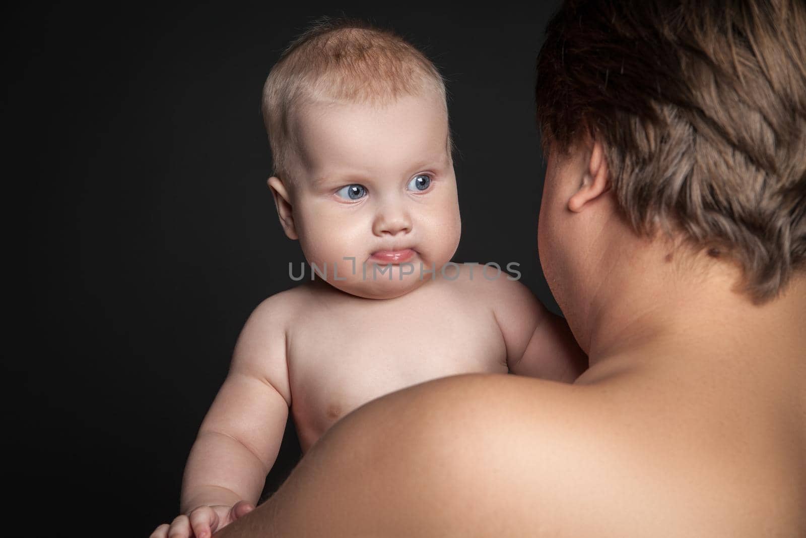 Cute baby looking over father's shoulder, isolated on black