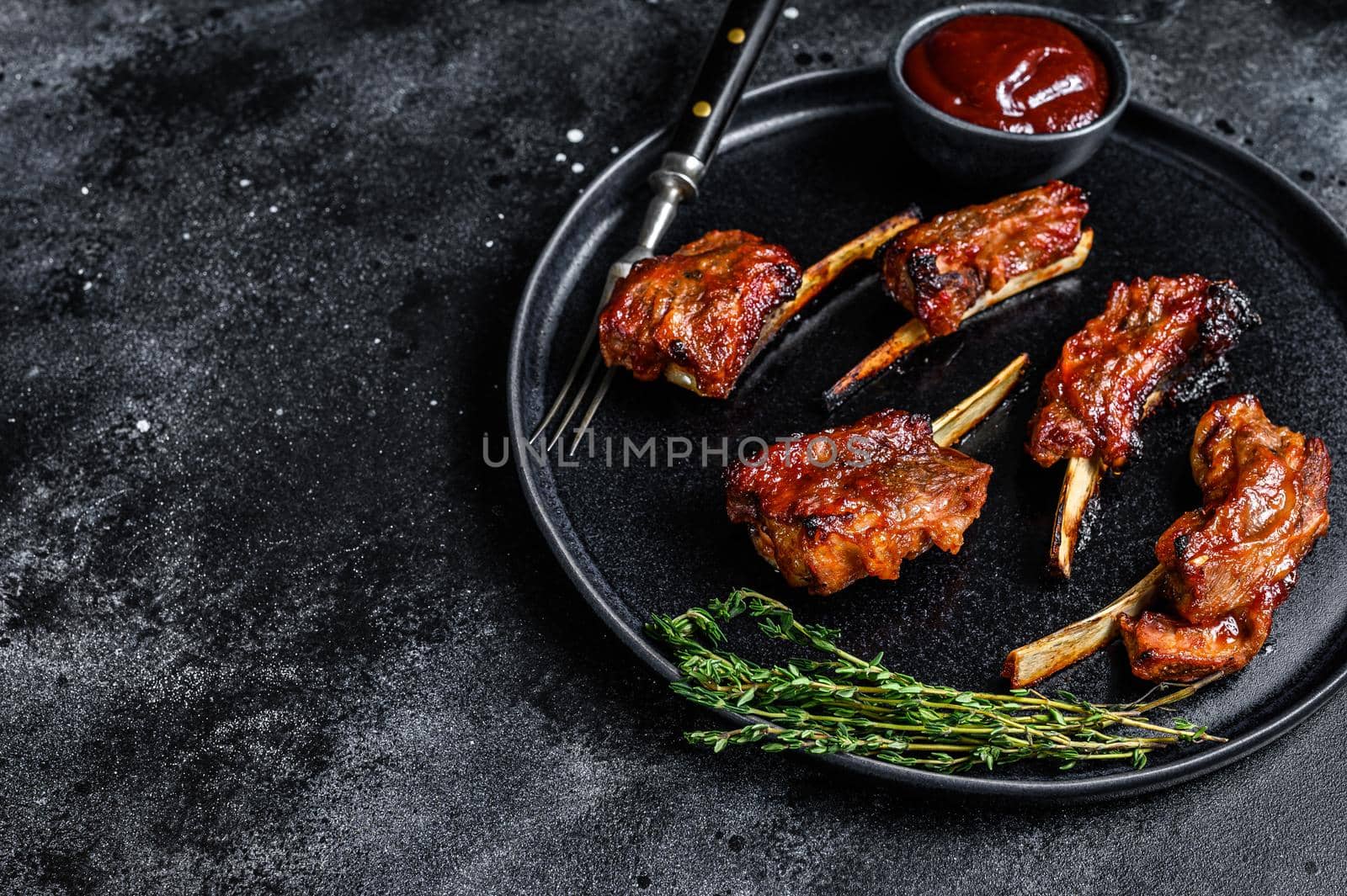 BBQ grilled sliced veal short spare loin ribs. Black background. Top view. Copy space.
