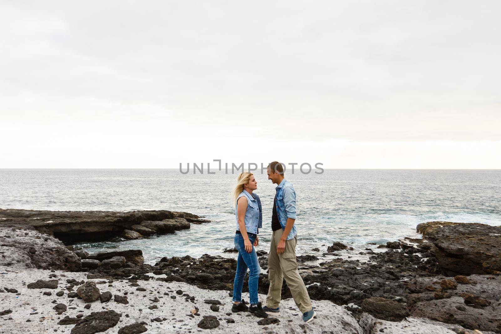 Romantic couple on the beach in a colorful sunset in the background. A guy and a girl at sunset on the island of Tenerife by Andelov13