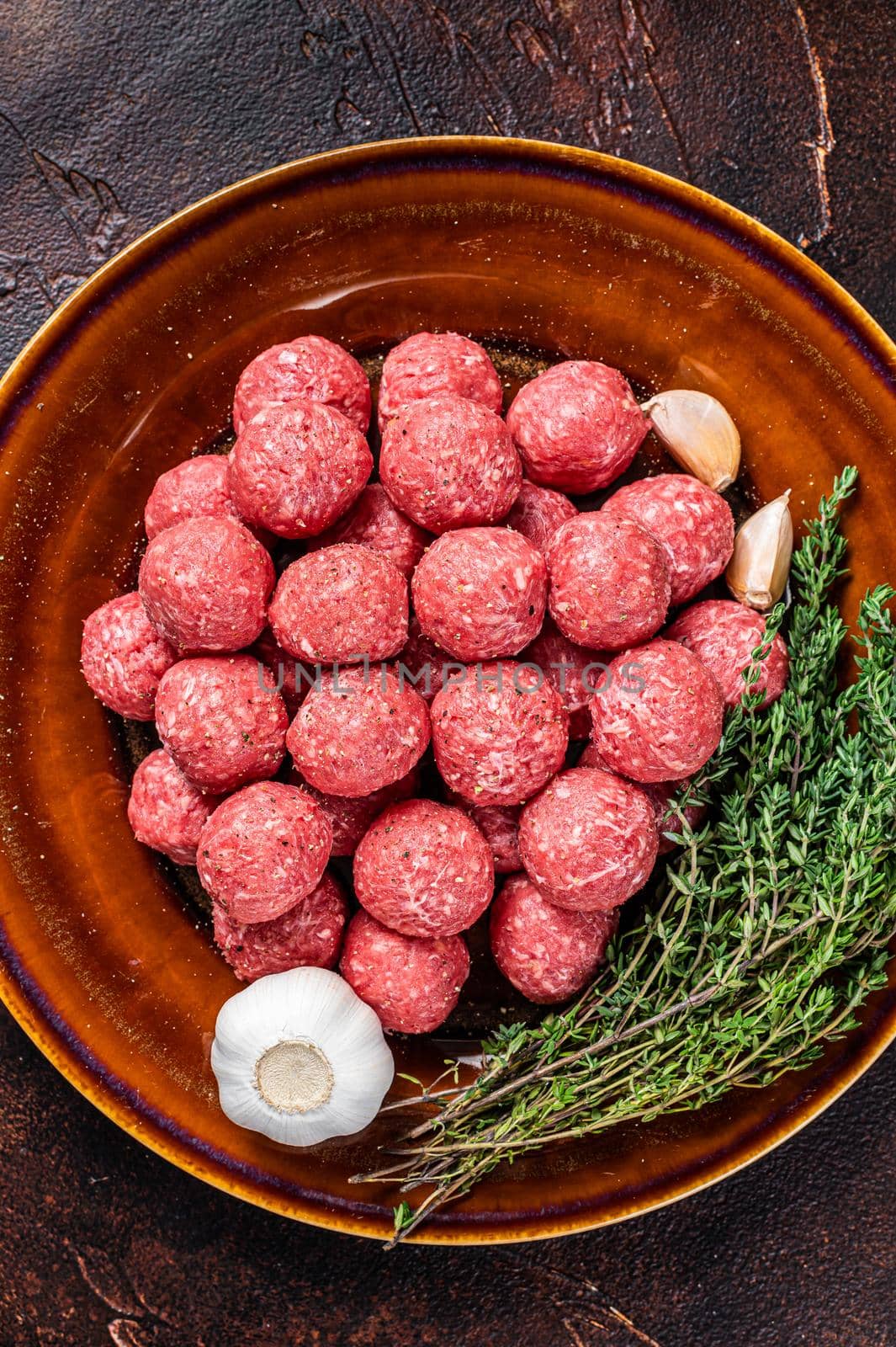 Raw meatballs from mince lamb mutton meat with thyme on rustic plate. Dark background. Top view.