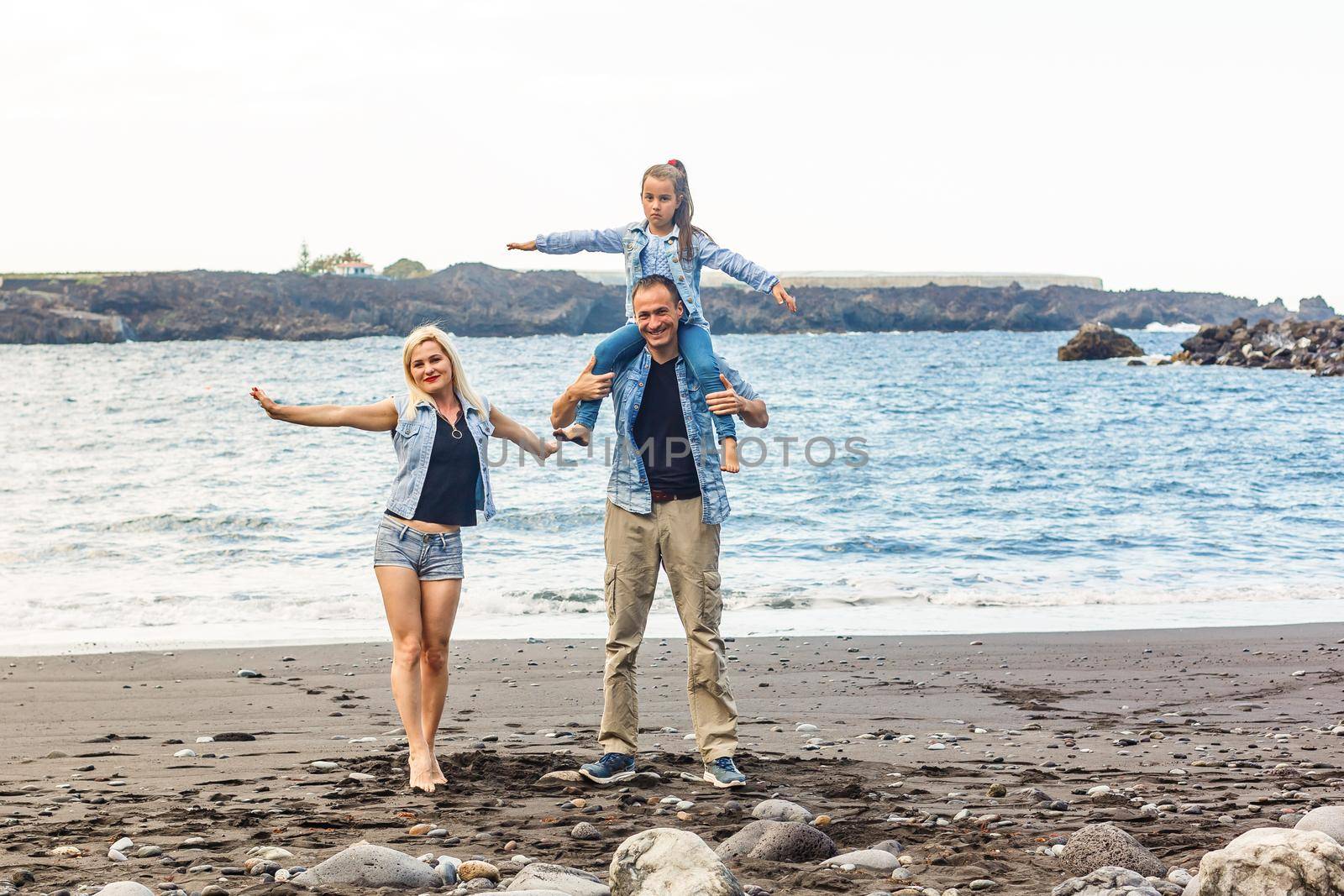 Happy family standing on the beach on the dawn time by Andelov13