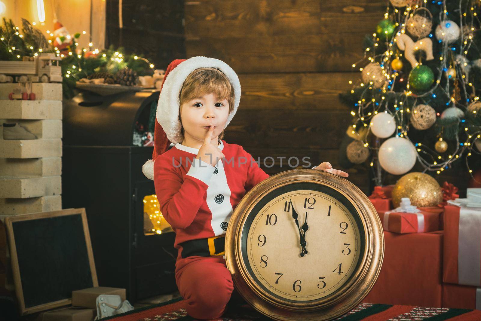 Cute child with alarm clock christmas. New year clock, time for christmas night. Kid boy is waiting for the New Year