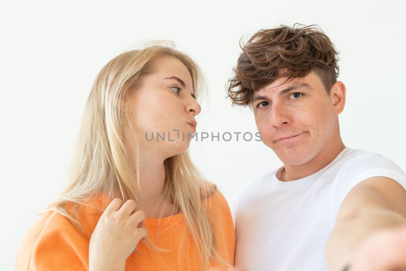 Charming young couple cute blond girl girl take a selfie posing over white background. Concept a young couple of teenagers or millennials In love