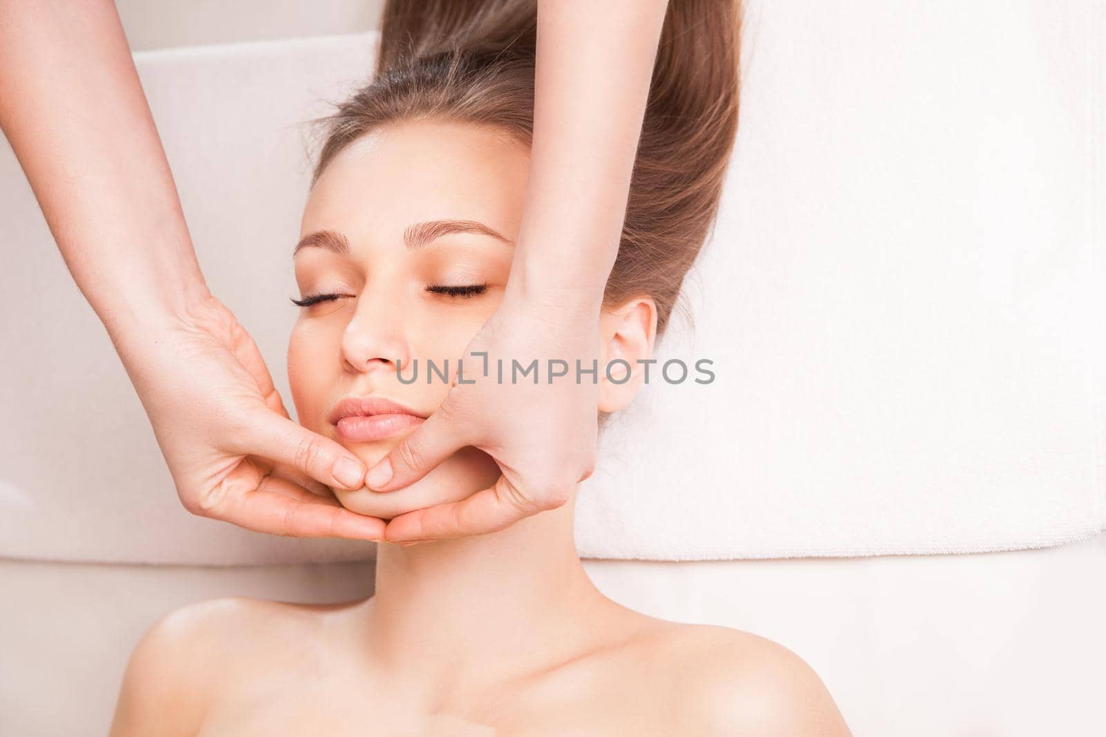 Young bright woman receiving head massage in spa center