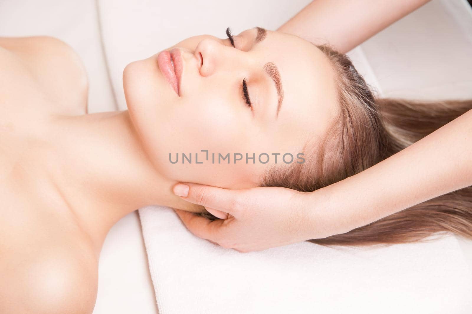 Young bright woman receiving head massage in spa center