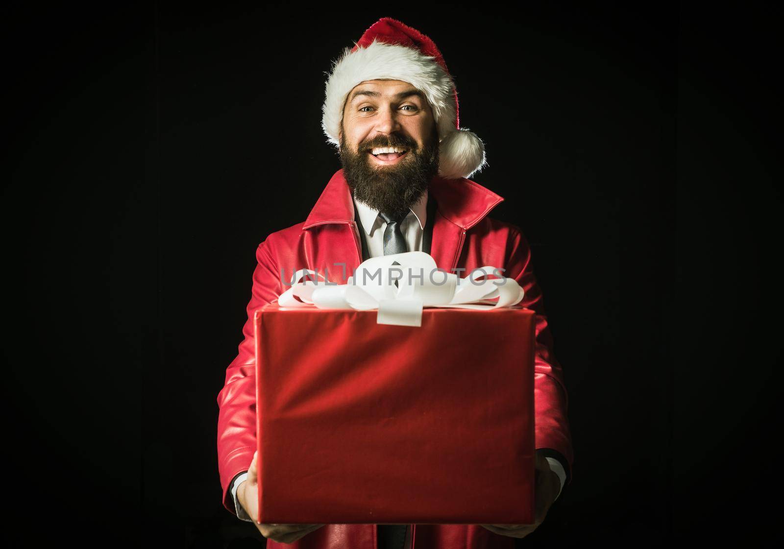 Surprised santa with christmas gift isolated on black. Funny Santa man in winter clothes wishes merry Christmas