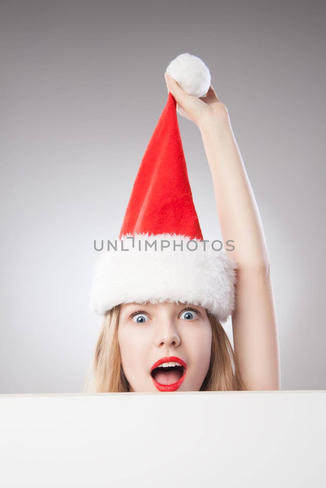 Beautiful christmas woman in santa hat holding empty board isolated on white background