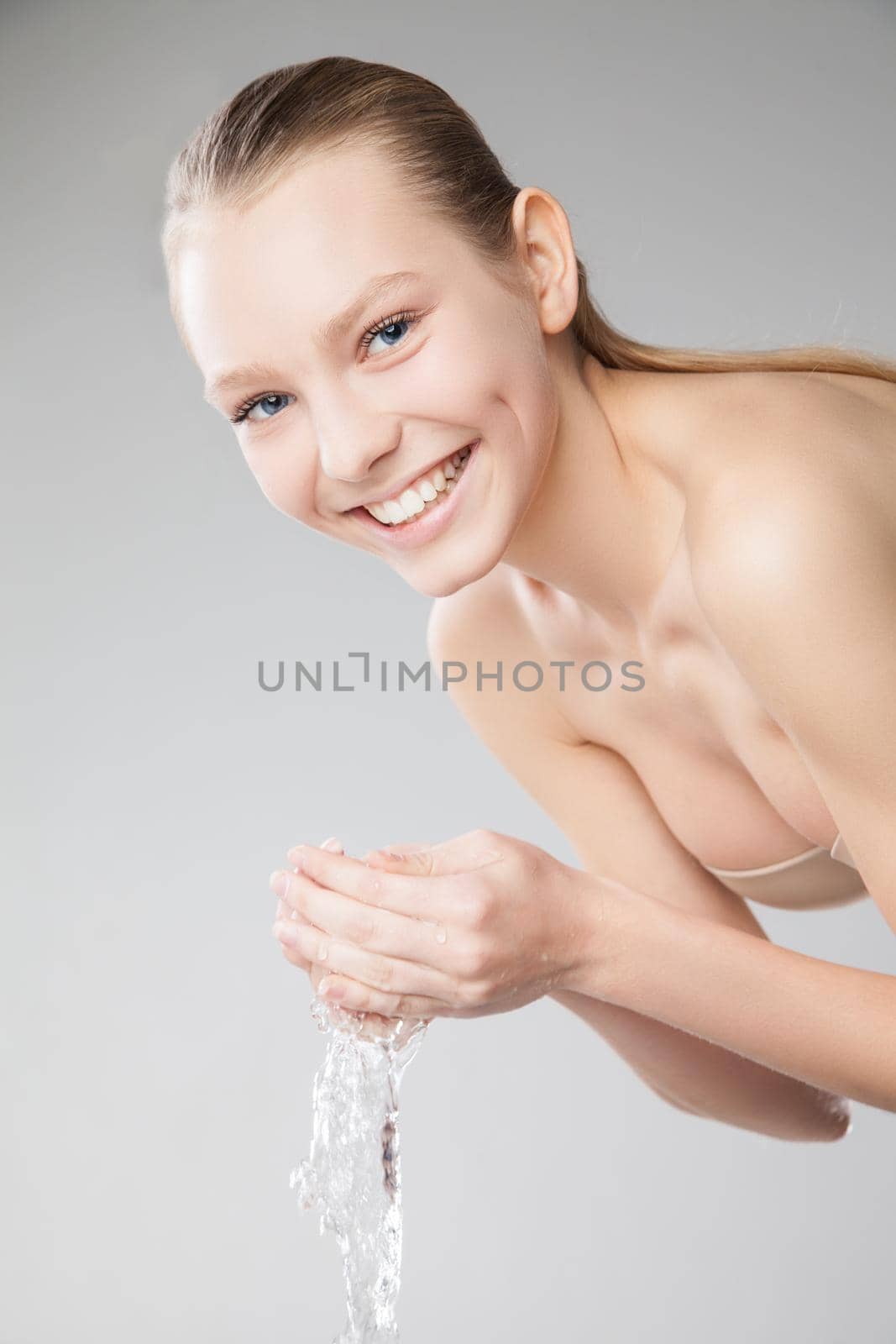 Closeup portrait of a beautiful woman washing her clean face with water