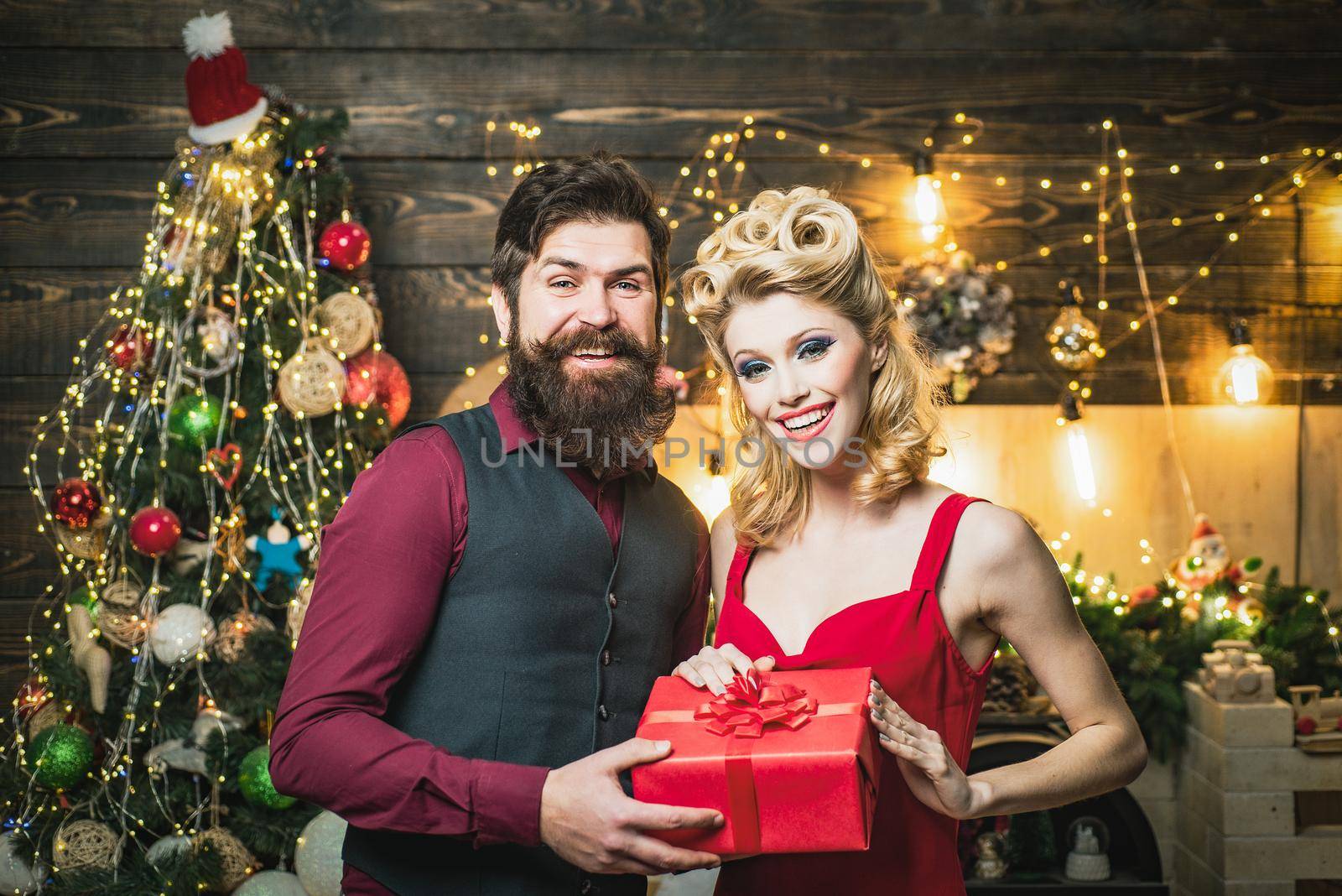 Funny couple holding a gift box. Beautiful happy couple with gift at Christmas party