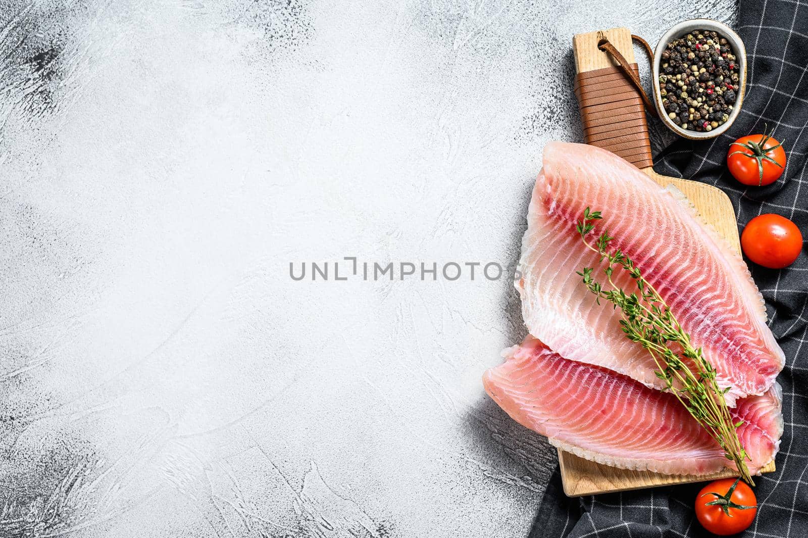 Raw fish tilapia on the cutting Board. Gray background. Top view. Copy space by Composter