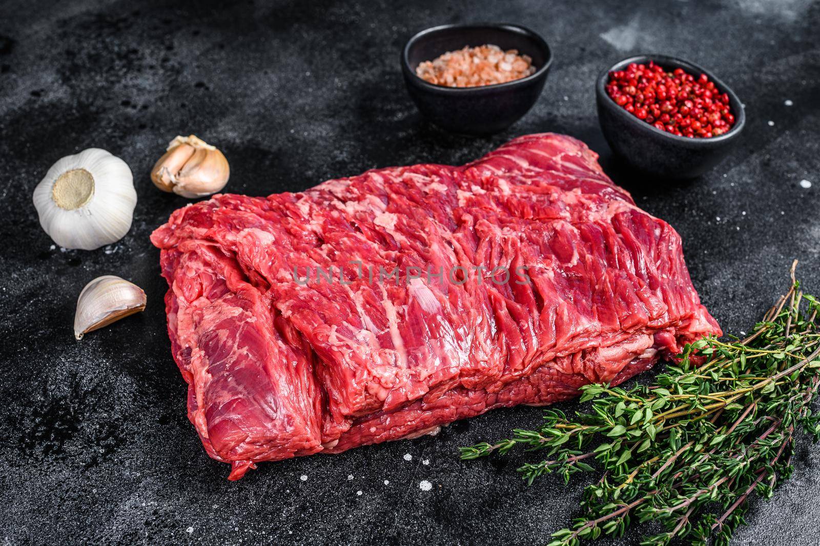 Raw fresh marble beef brisket meat with herbs. Black background. Top view.