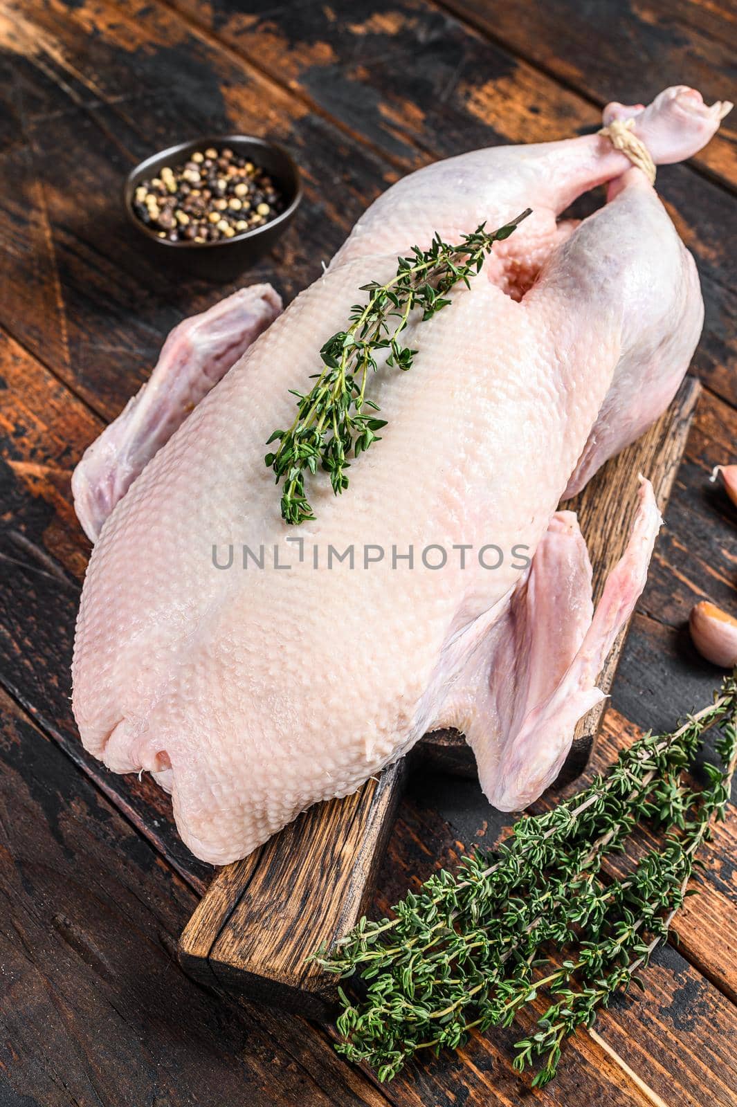 Raw whole mallard duck, poultry meat with herbs. Dark wooden background. Top view.