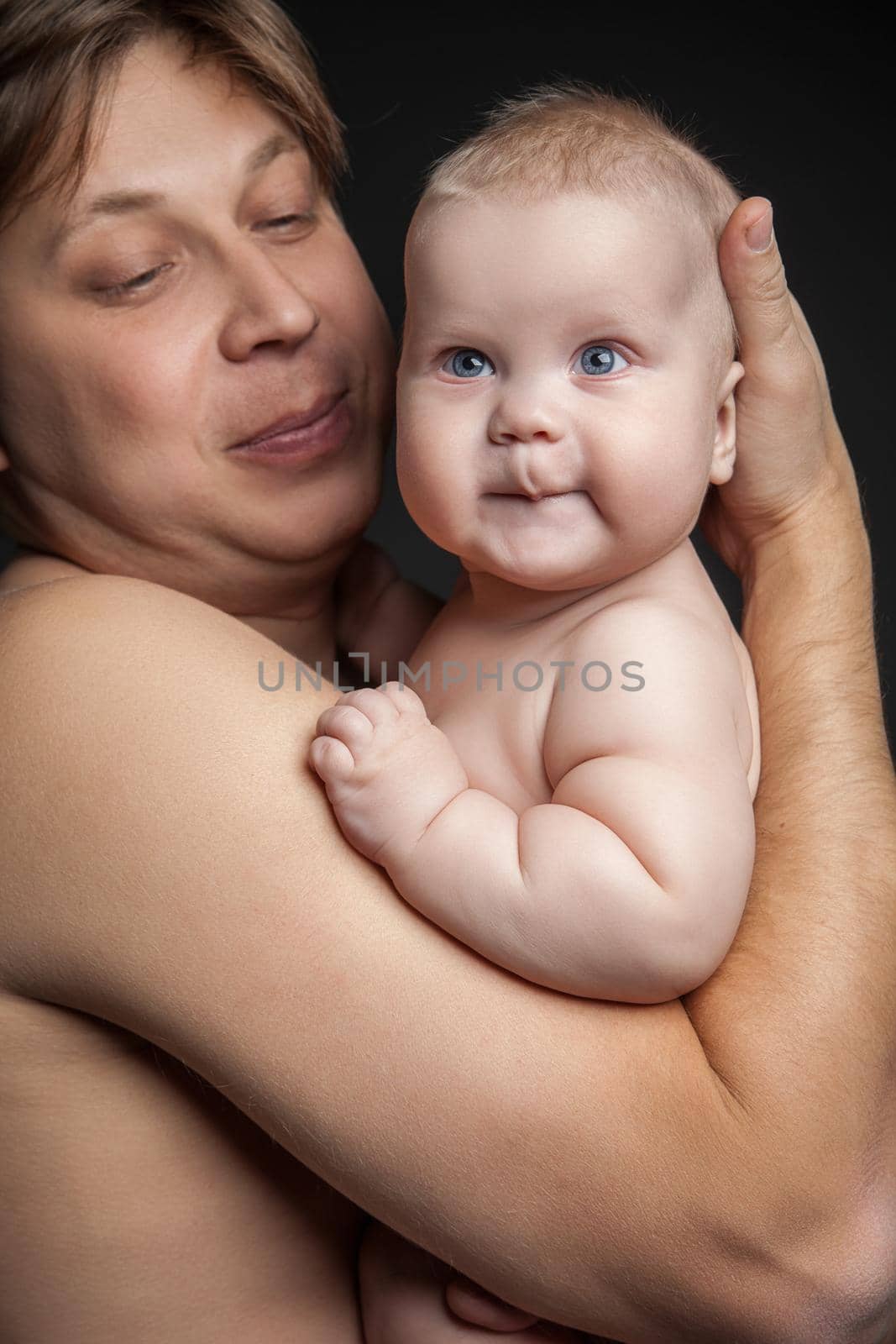 Portrait of happy man holding cute baby boy and looking at him. Close up