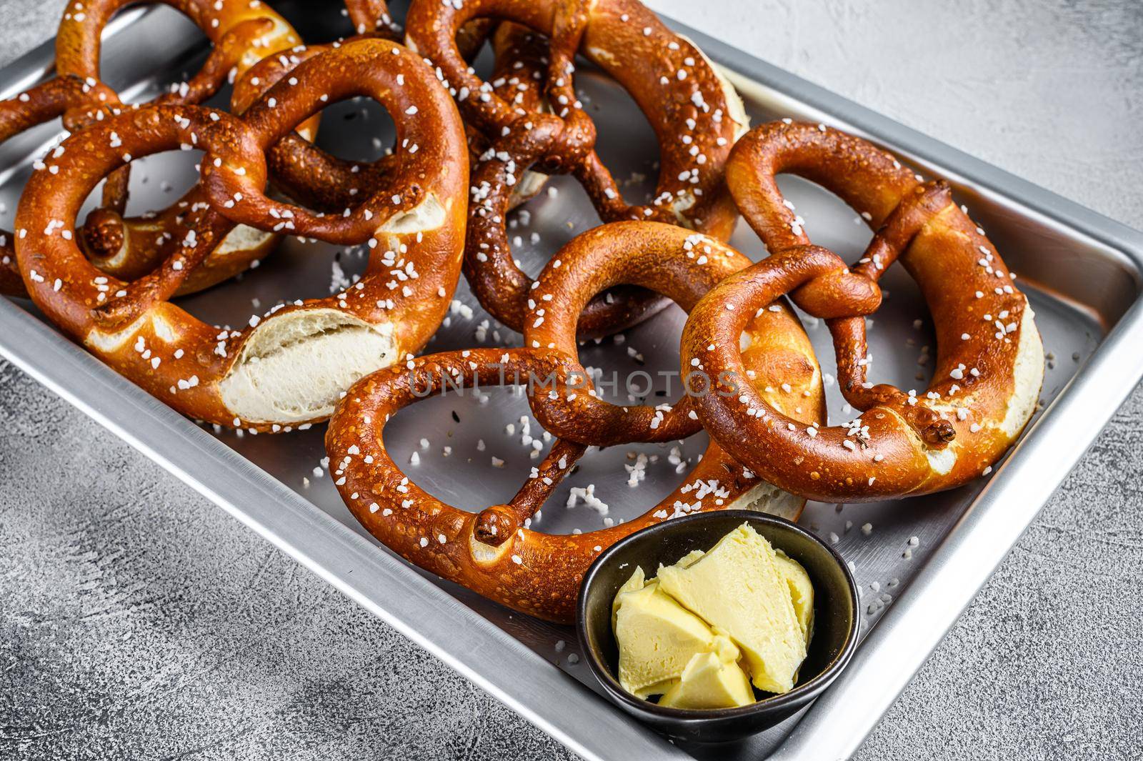 Salted pretzels with sea salt on a kitchen baking pan. White background. Top view.