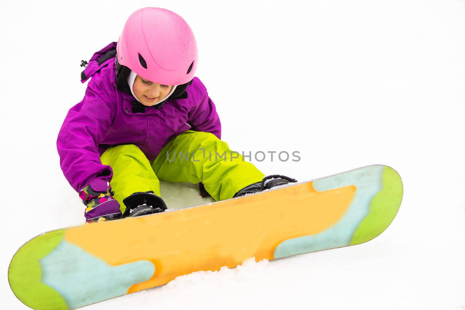 Snowboard Winter Sport. little girl learning to snowboard, wearing warm winter clothes. Winter background.