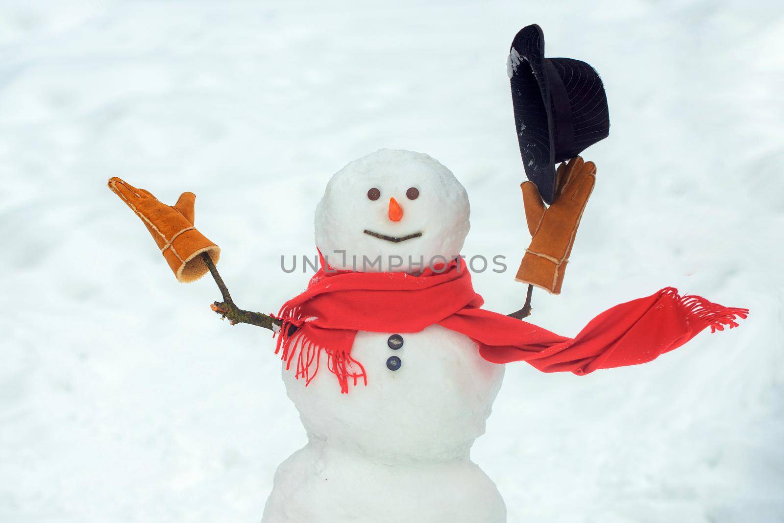 Snowman with hat and scarf in winter outdoor. Hello winter. Happy smiling snow man on sunny winter day. by Tverdokhlib