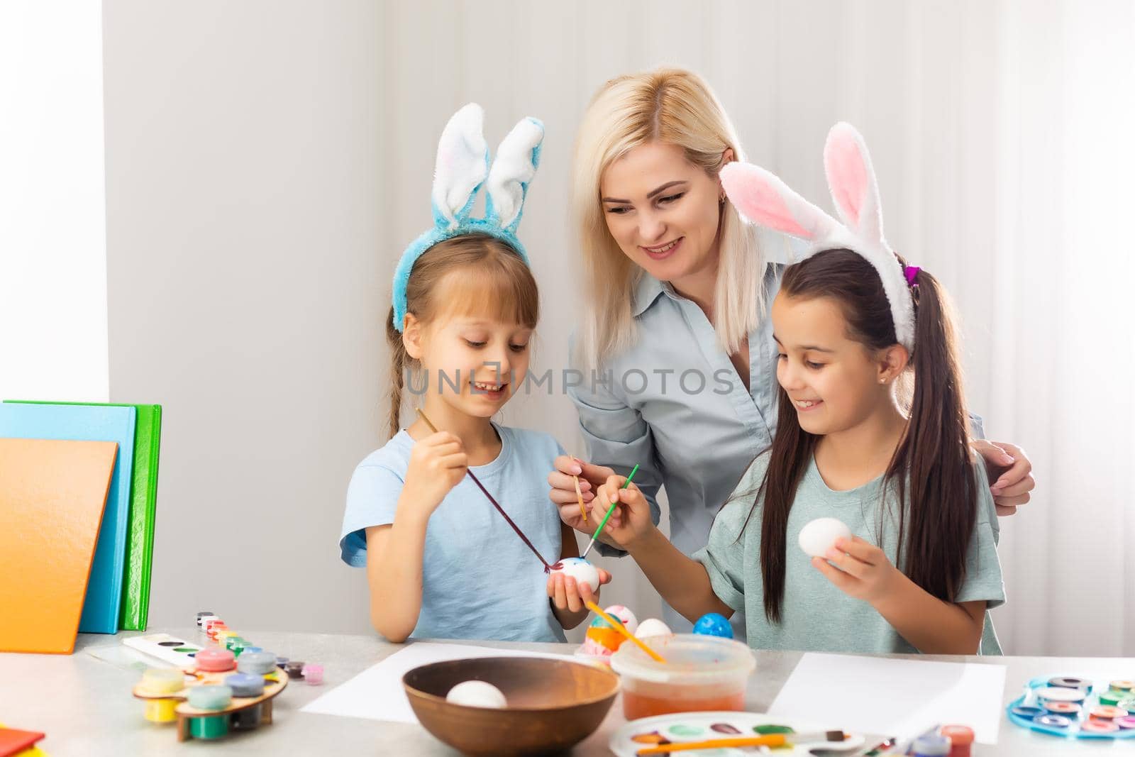 Young mother and her two daughters painting Easter eggs by Andelov13