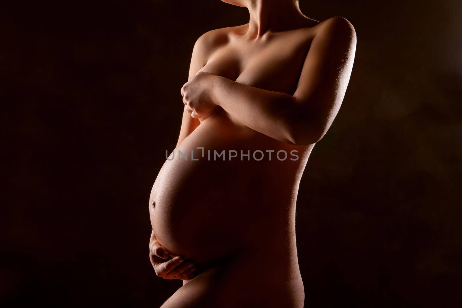 Pregnant woman silhouette over black background. Side view