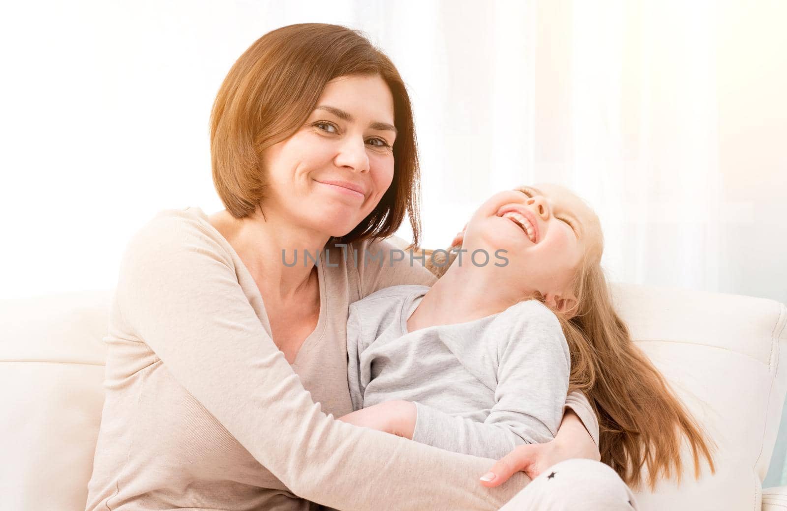 Mother and little daughter smiling, Pretty girl making her mother smile. Daughter and mom having fun together