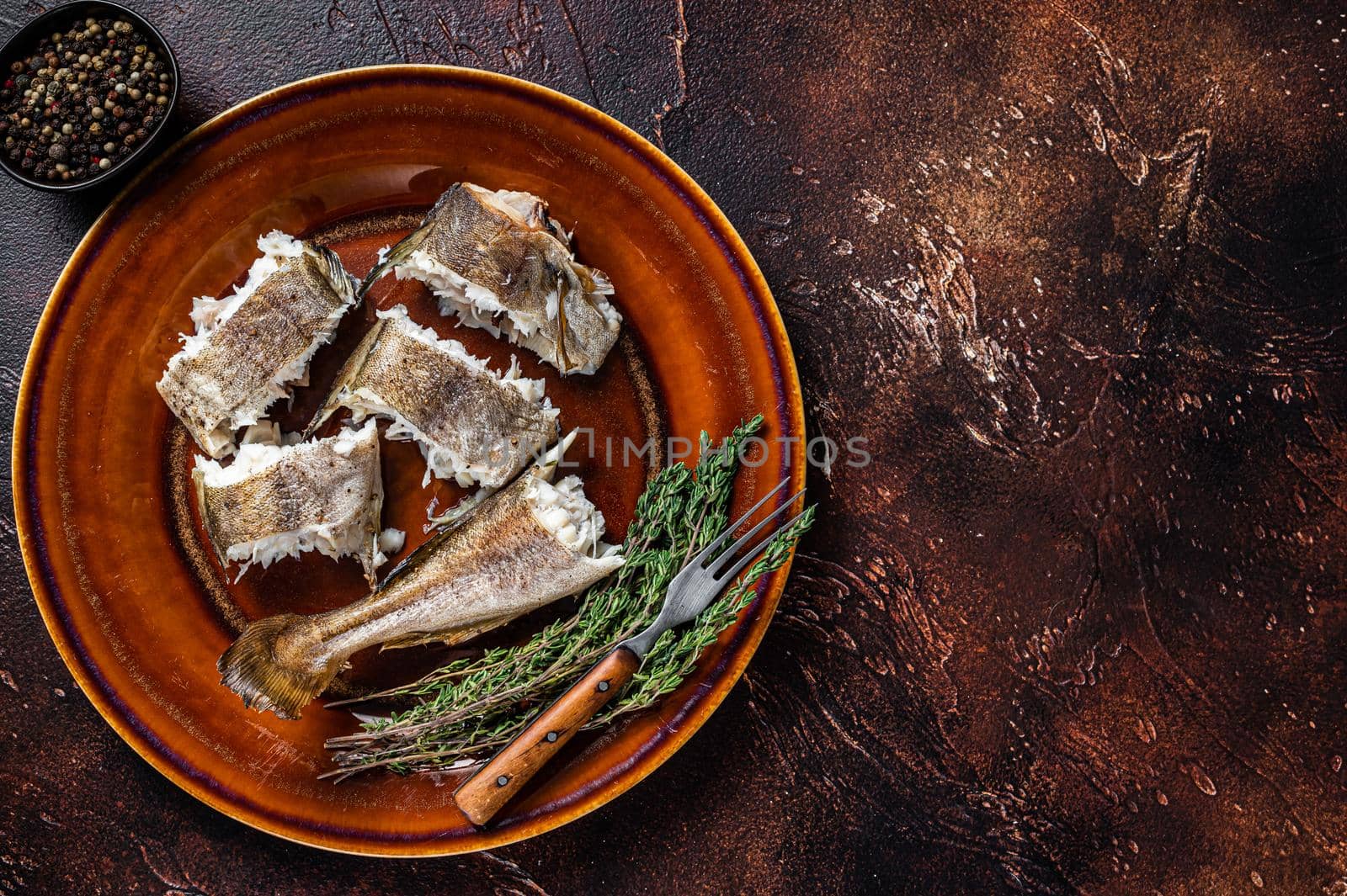 Baked cod white fish in a plate. Dark wooden background. Top view. Copy space by Composter