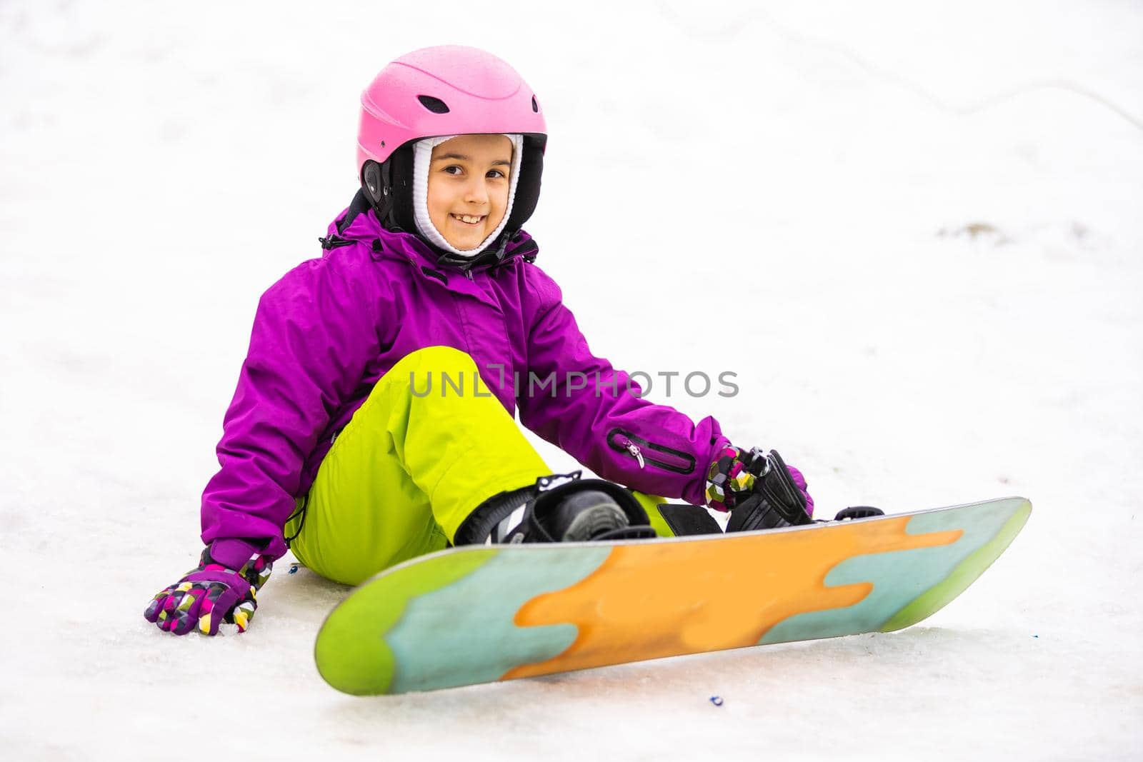 Little Cute Girl Snowboarding at ski resort in sunny winter day.