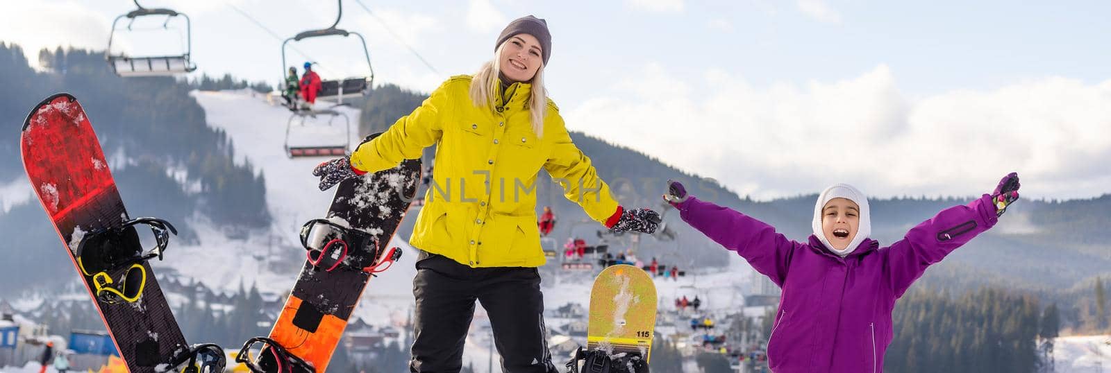 mother and daughter with snowboards at winter resort by Andelov13