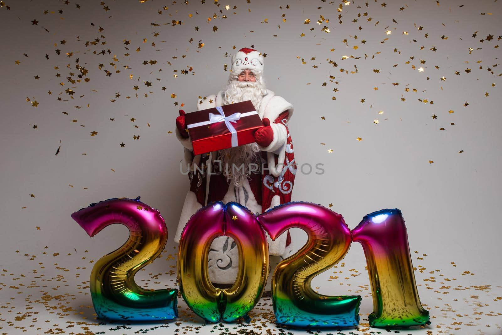 Xmas and New Year 2021 celebrating, Santa with gift, balloons and golden confetti congratulate with winter holidays by StudioLucky