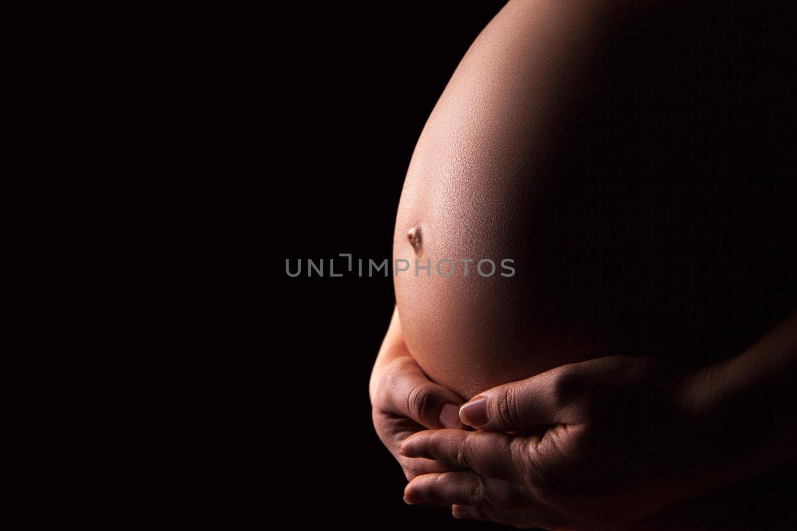 Pregnant woman silhouette over black background. Side view