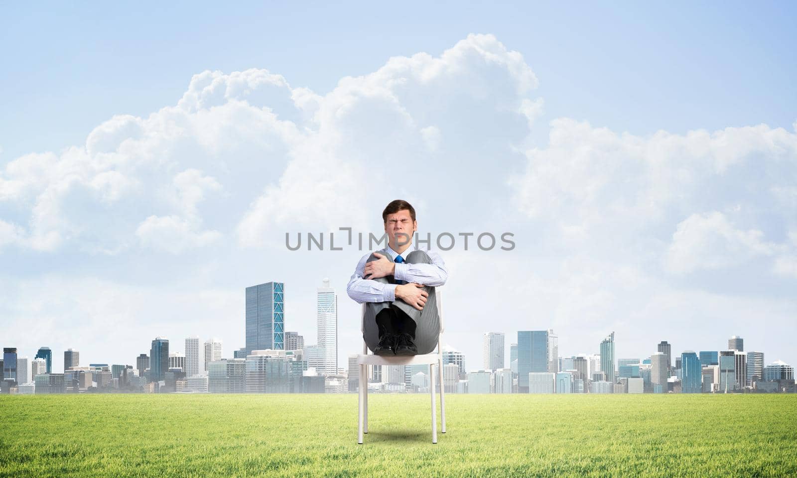 scared businessman sitting on a chair with his hands clasped his knees