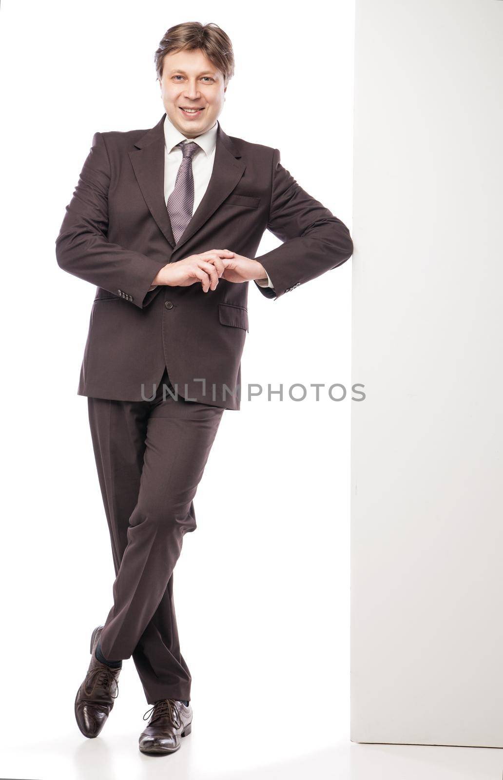 Man leaning against empty board while smiling to camera on white background