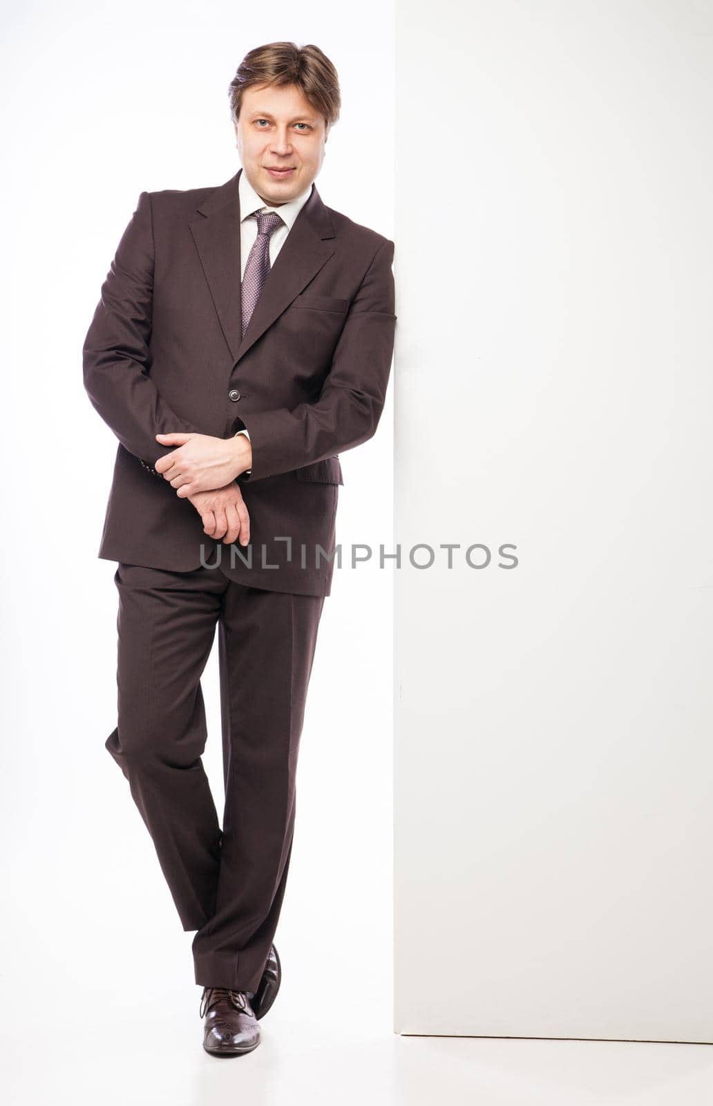 Man leaning against empty board while smiling to camera on white background
