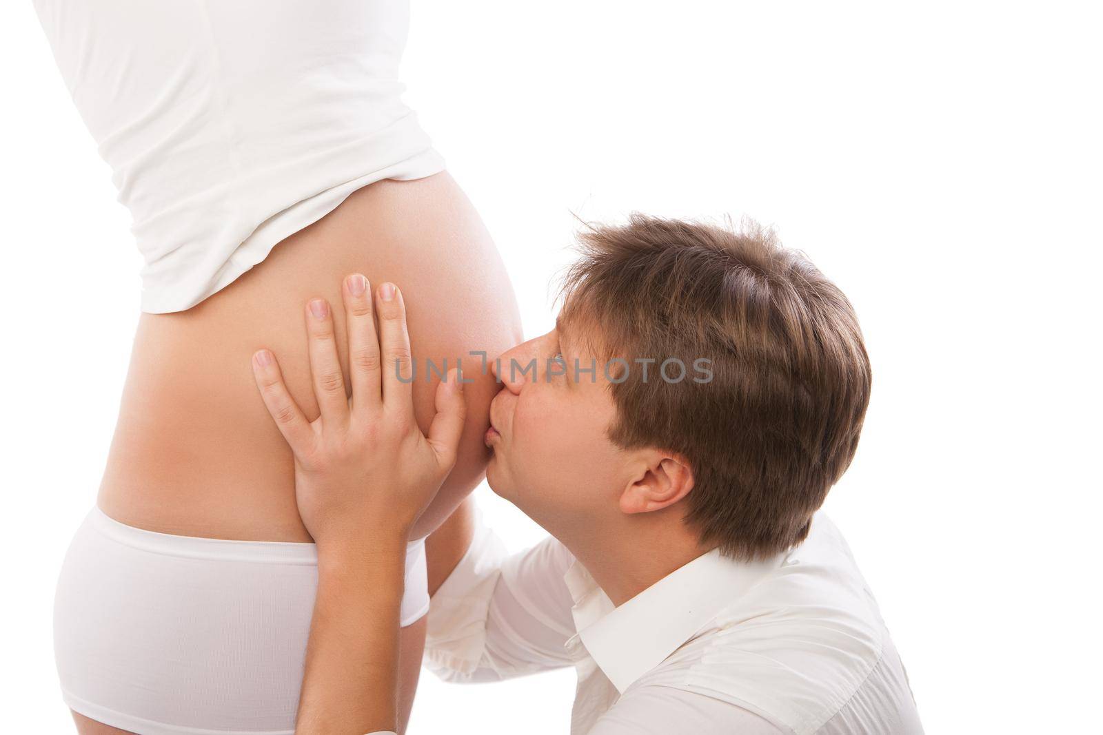 Happy young father kissing the belly of his pregnant wife
