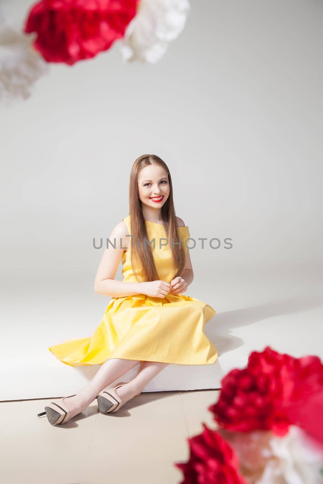 Portrait of beautiful smiling model sitting on floor in yellow dress.Studio shot.