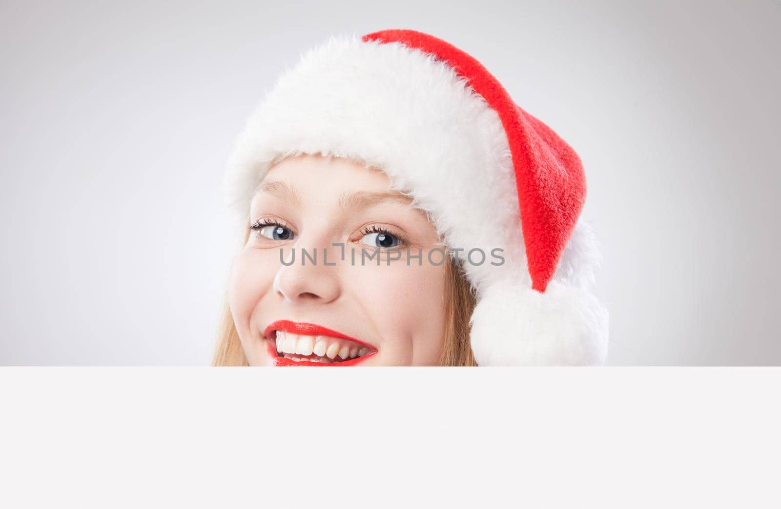 Beautiful christmas woman in santa hat holding empty board isolated on white background