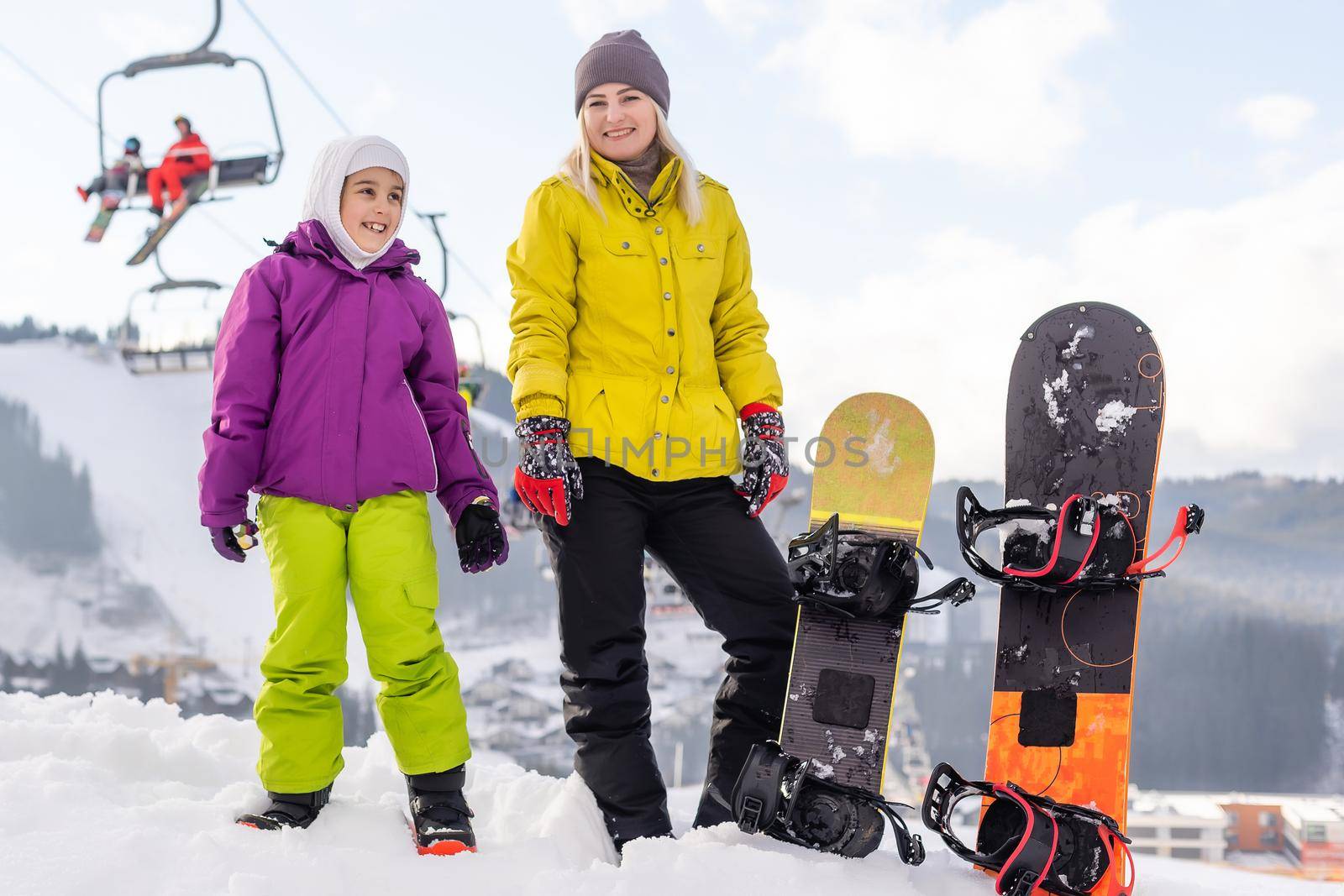 Mother and daughter with snowboards are playing in the snow