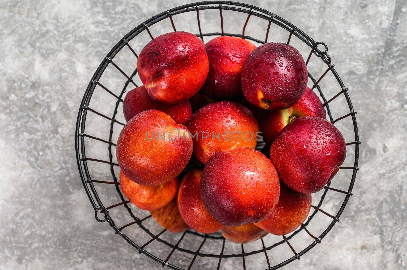 Ripe red nectarines in a basket. Gray background. Top view.