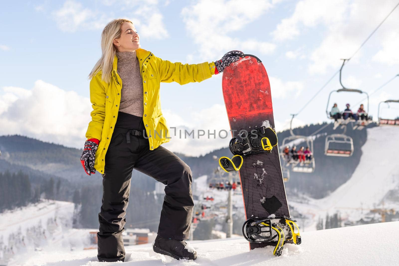 Young woman with snowboard on the slope of hill at winter resort by Andelov13