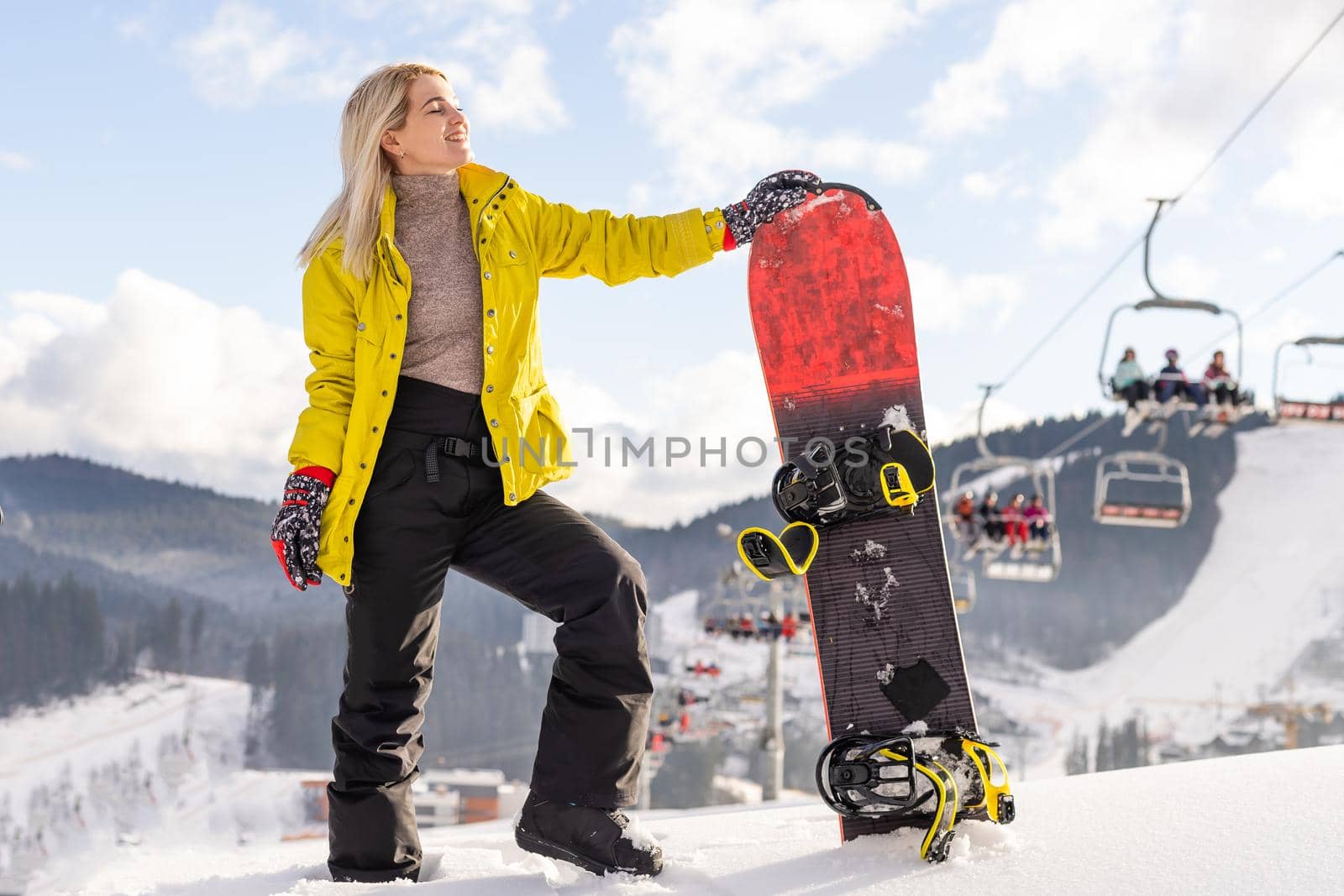 Young woman with snowboard on the slope of hill at winter resort