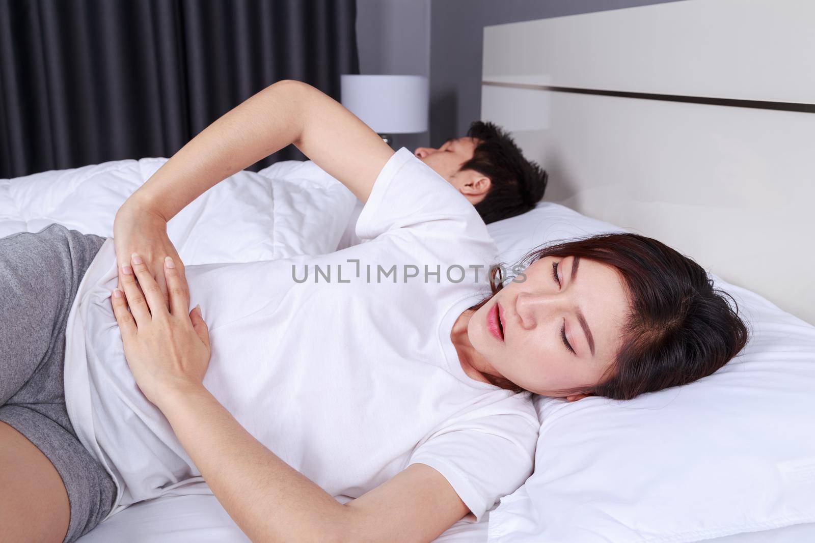 woman stomach pain on bed with her hunsband by geargodz